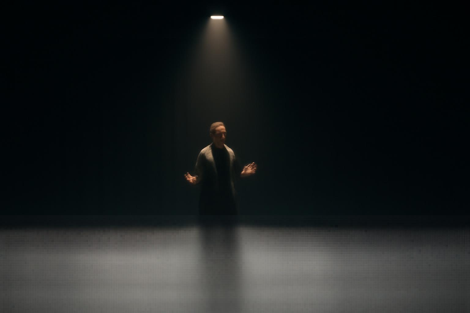 Actor standing alone on stage under a spotlight