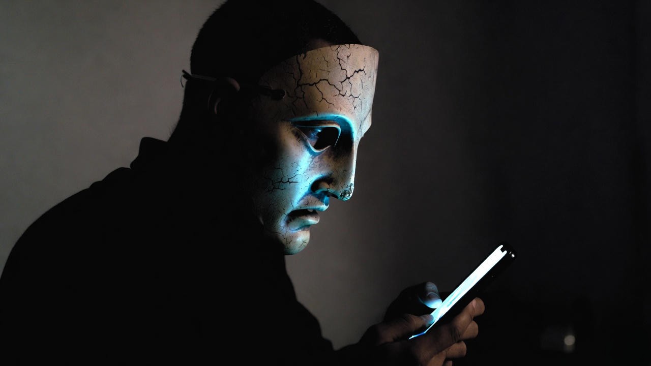 Modern figure in tragedy mask scrolling on phone – Shakespeare’s warnings about folly and self-deception in the digital age