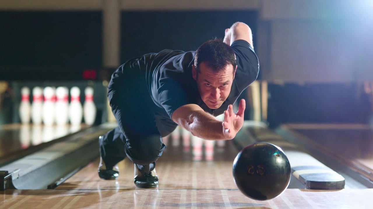 Professional bowler releasing a reactive bowling ball with perfect form on a heavy oil lane.