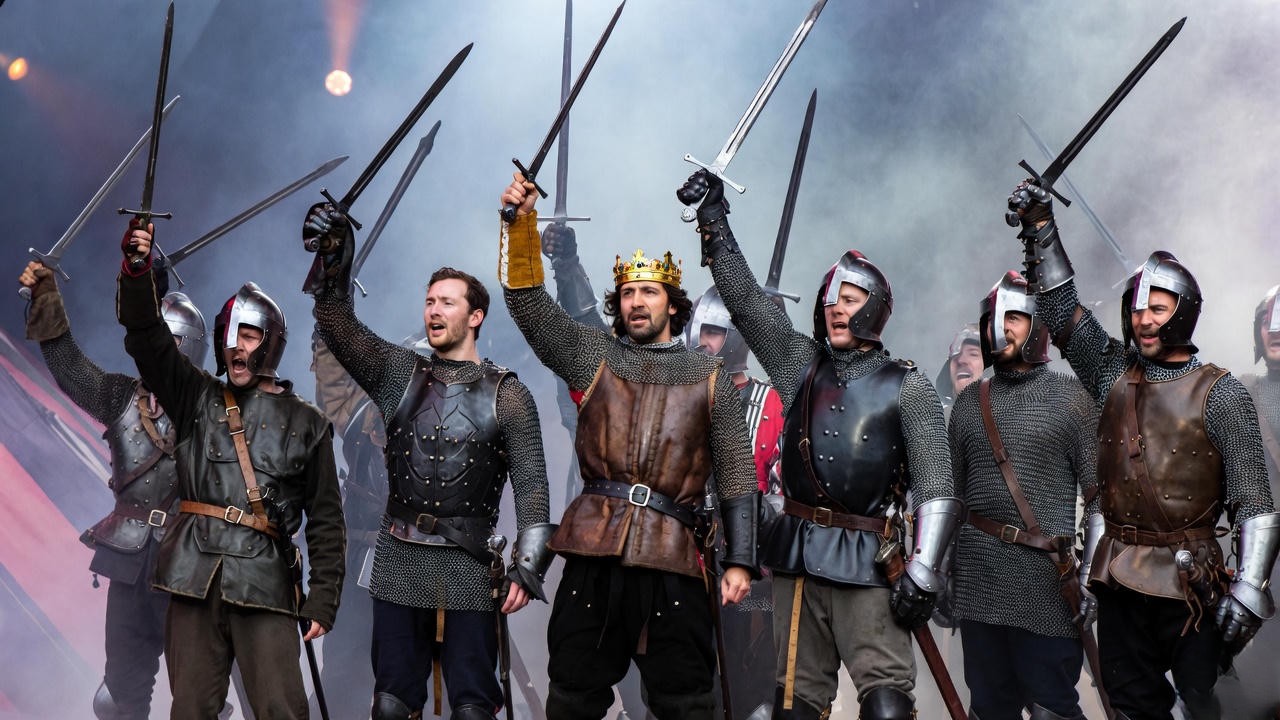 Ensemble cast as soldiers in Henry V play rallying on stage during epic theatre performance