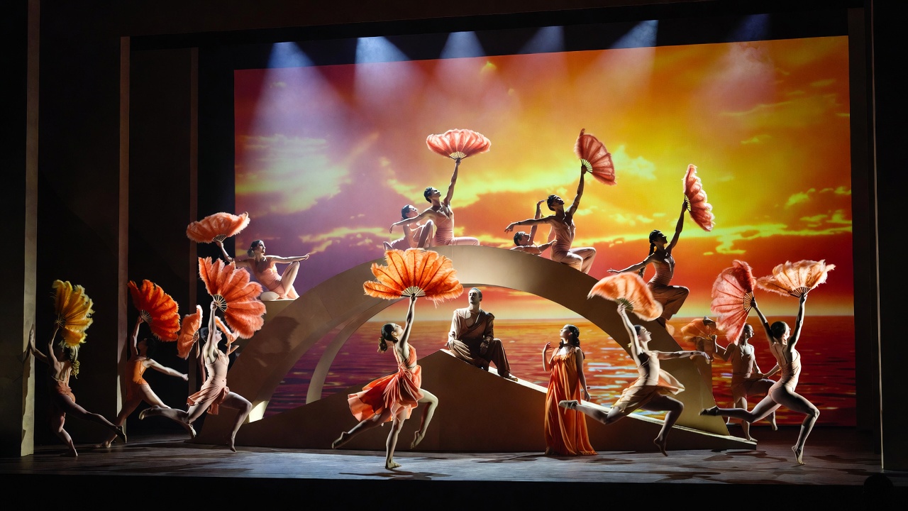 Antony surrounded by feathered dancers and sunset projections in the Metropolitan Opera's 2025 production of John Adams Antony and Cleopatra Shakespeare adaptation
