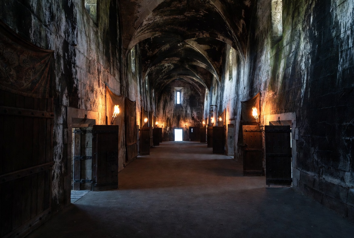 Confined stone corridors of Elsinore Castle illustrating entrapment and surveillance themes in Hamlet