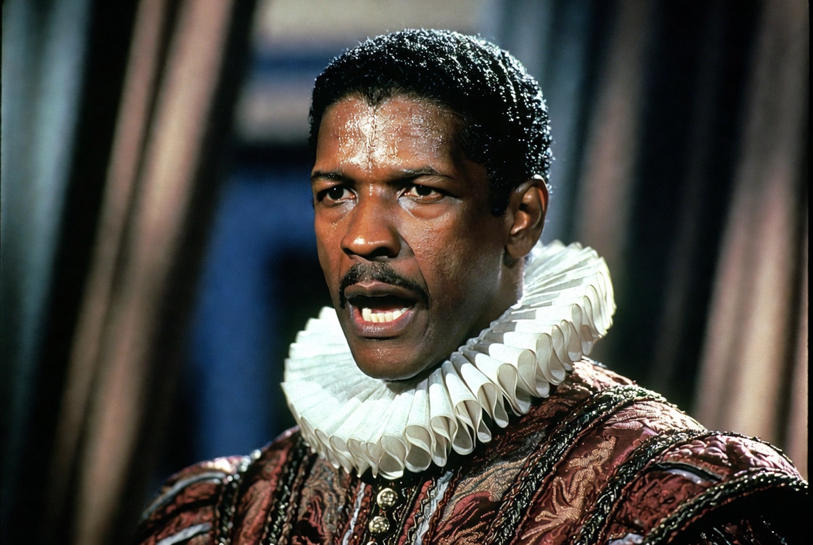 Extreme close-up of Denzel Washington as Othello on the Broadway stage, his face captured mid-monologue with raw power and inner torment, furrowed brow, intense gaze, subtle sweat under hot stage lights, wearing an intricately detailed Elizabethan doublet and crisp white ruff collar, dramatic side lighting creating deep shadows that accentuate facial emotion and character depth, soft blurred background of stage curtains, photorealistic, high dynamic range, cinematic theatrical photography, 16:9 aspect ratio, no text or lettering.