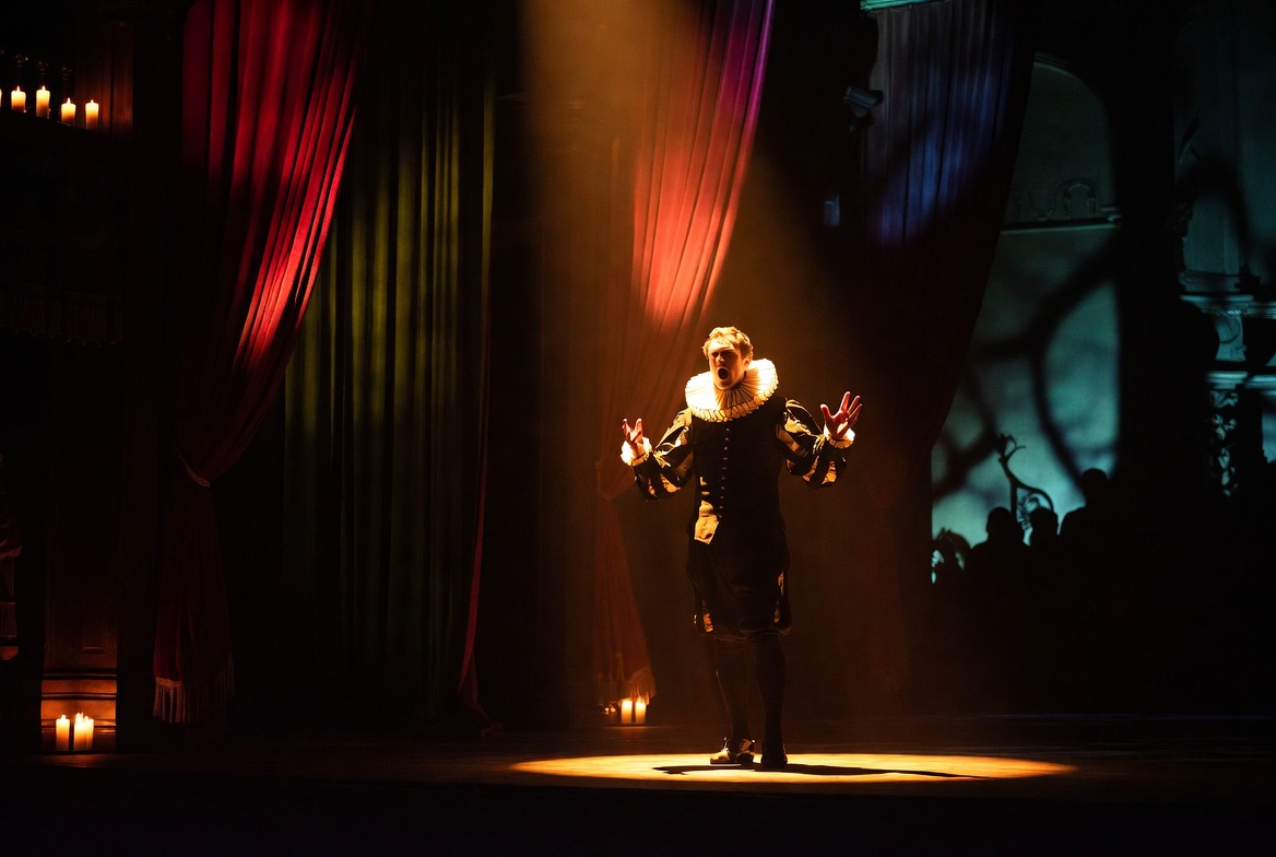 Shakespearean actor performing a dramatic soliloquy on an Elizabethan stage